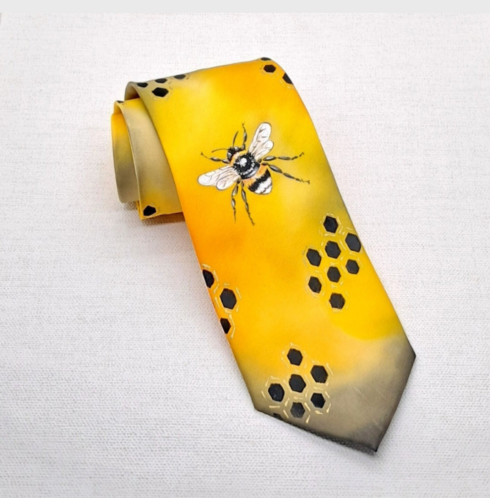 A yellow silk necktie that is hand painted with two honey bees and honeycomb. 